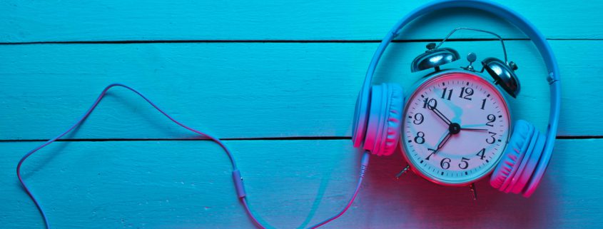 Imagem mostra um headset colocado sobre um relógio com alarme.