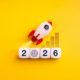 Rocket launching above 2026 cubes with target icon and growth graph on yellow background, symbolizing business startup, creative market, innovation strategy, new year goals, and future success.